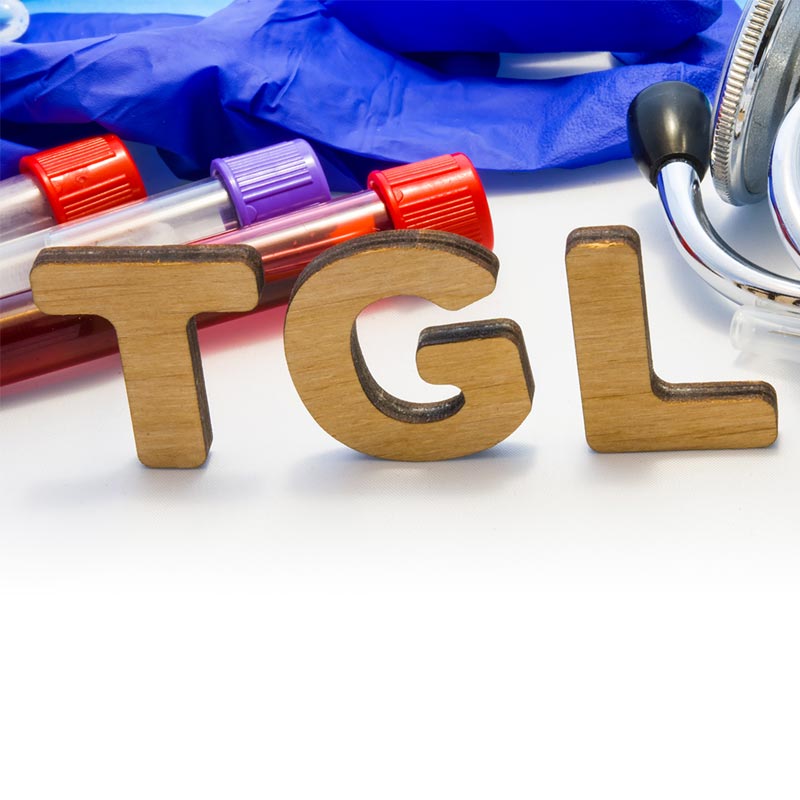 wooden letters TGL on table with vials of blood rubber gloves and stethoscope
