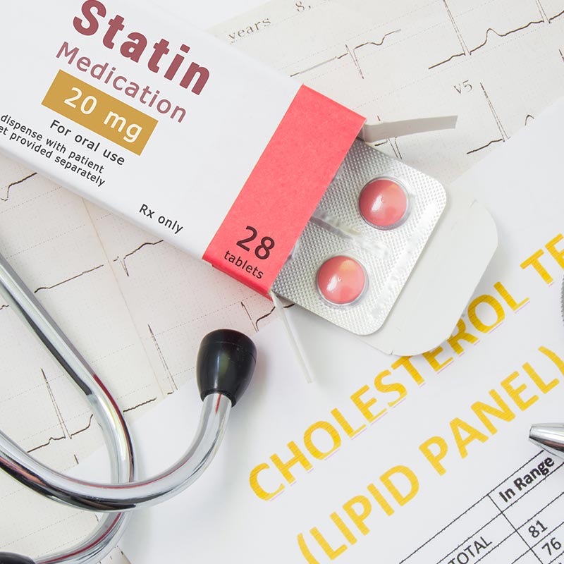 statin medication and cholesterol test results on table with stethoscope